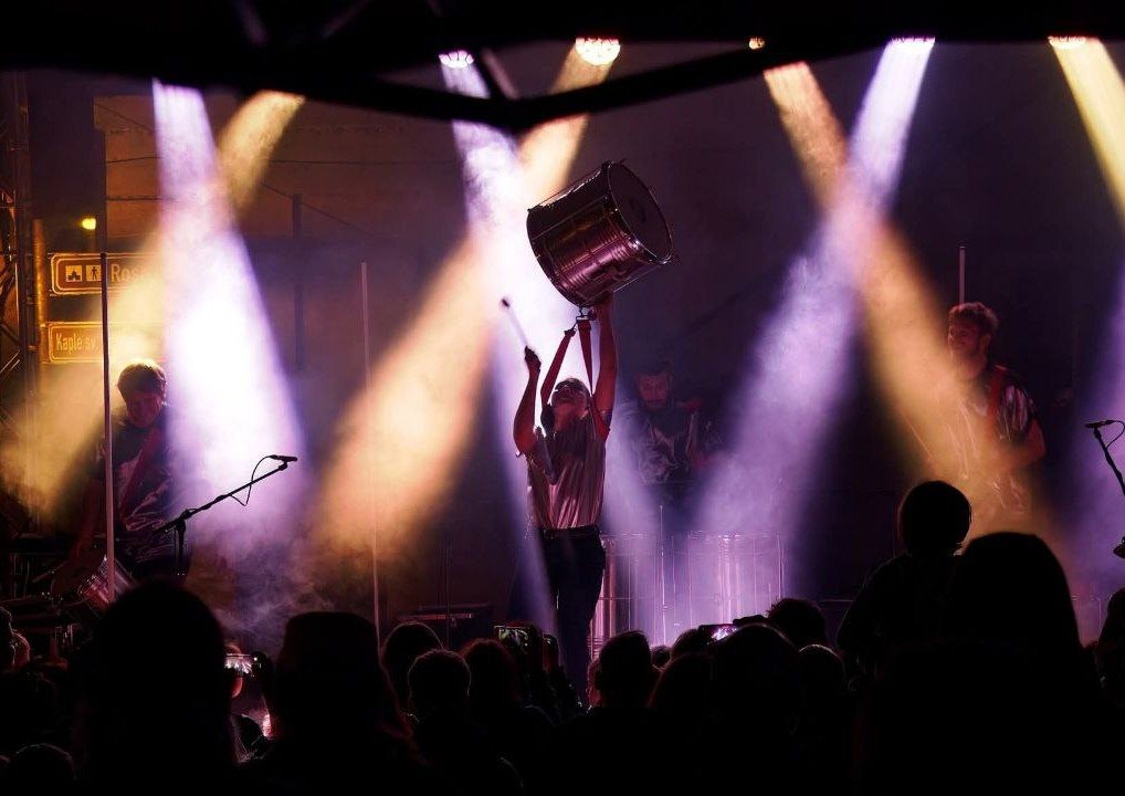 Lifting a drum overhead in stage lights at a Brazilian percussion concert